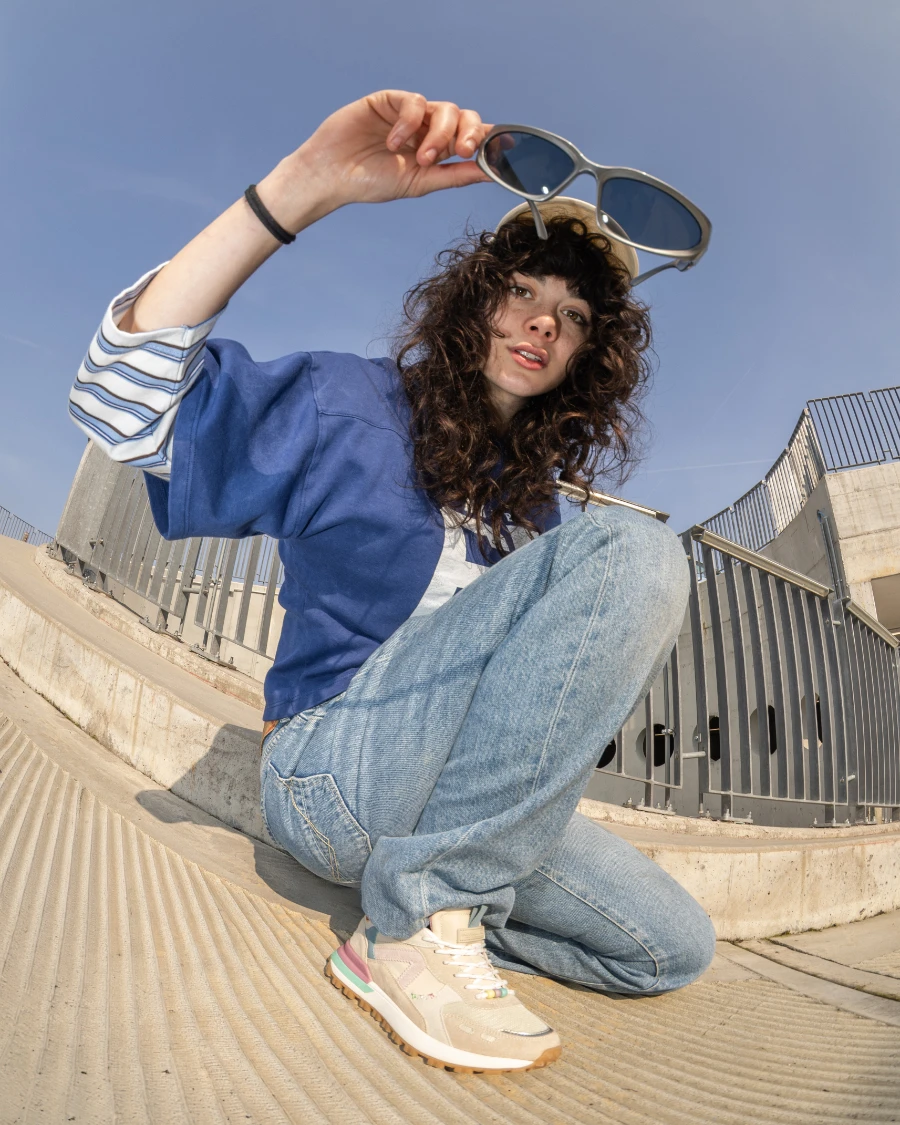 Donna con sneaker Cotton Belt beige e dettagli pastello su rampa in cemento.