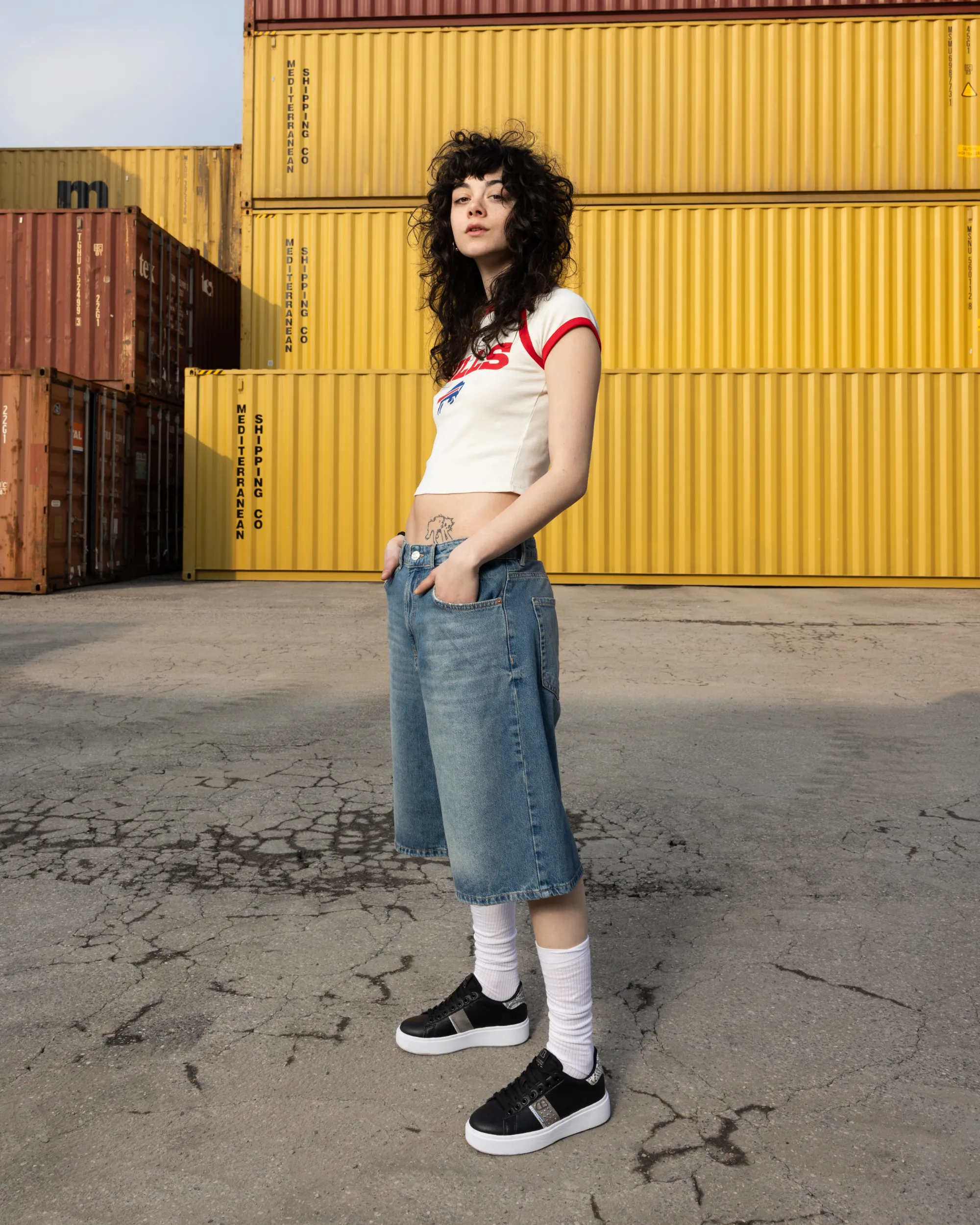 Woman wearing black platform Cotton Belt sneakers and tall white socks.